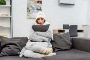 woman-in-sweats-hugging-pillow-looking-cold