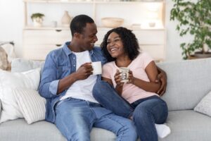 young-couple-sitting-on-couch-looking-happy