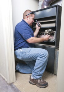 technician-using-flashlight-to-look-at-wiring-in-furnace