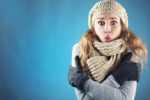 woman-bundled-up-looking-cold-on-blue-background
