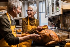 senior-couple-taking-turkey-out-of-oven-at-thanksgiving