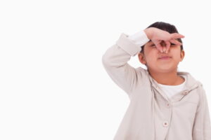 Girl pinching her nose against a white background